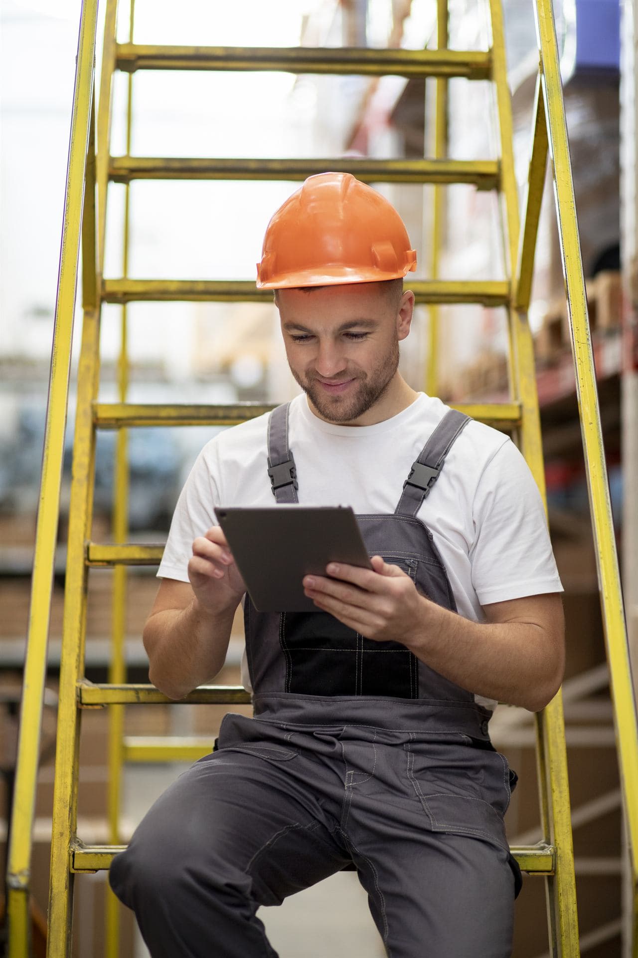 Obrero con casco naranja revisando información en una tablet en obra